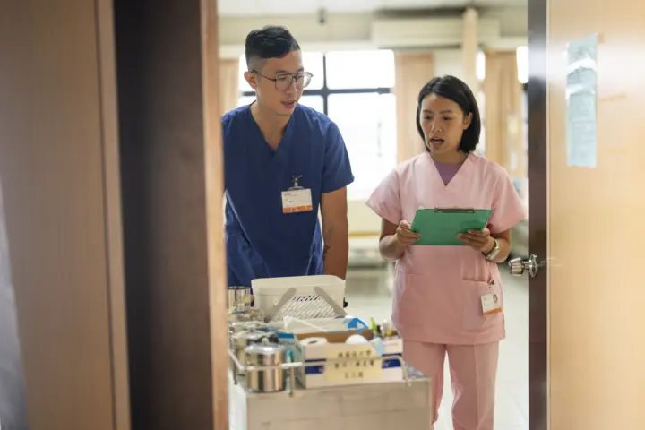 Male and female nurse pushing cart